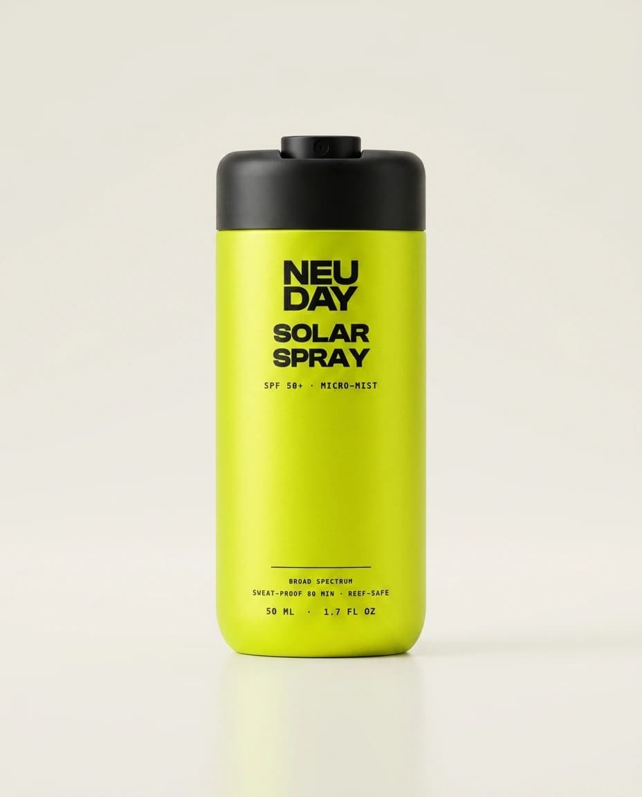 NEUDAY Solar Spray SPF 50+ — a volt-yellow 50ml aluminium micro-mist can with a matte-black cap and the NEUDAY wordmark, on a warm bone studio background